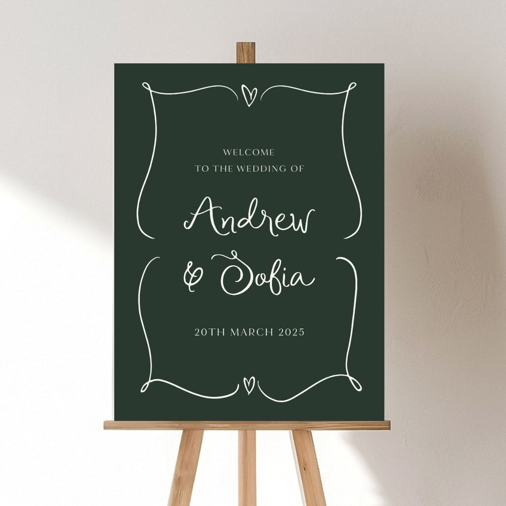 The Etched Design, Engagement Welcome Sign | Andrew & Sofia features a minimalist design with a dark green background and elegant white cursive text. Displayed on an easel, it reads, "Welcome to the wedding of Andrew & Sofia," with the date "20th March 2025" beneath. Decorative borders adorned with small hearts frame this personalized acrylic sign beautifully.