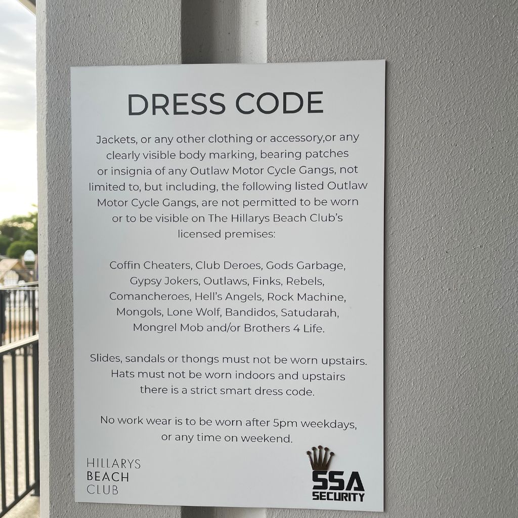 An Acrylic Business Sign titled "Dress Code" from Etched Design, crafted with Traffolyte material, at Hillarys Beach Club lists prohibited items and attire associated with various outlaw motorcycle gangs. Precision laser engraving details specific group names and general rules against visible tattoo body markings and illegal insignia.